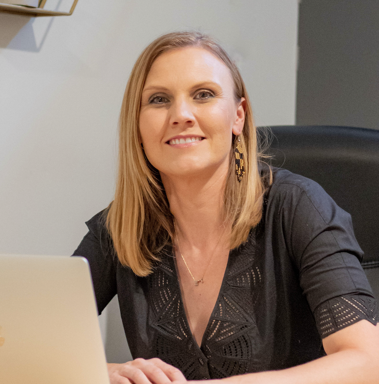 Mariah Kamei, Growth & Communications Leader, smiling at her desk.